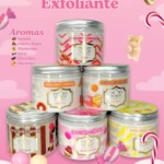 Pila de seis frascos de crema exfoliante corporal UMMER en colores pastel, con etiquetas que indican aromas como sandía, maracuyá y chocolate, sobre fondo rosa con dulces decorativos.