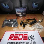 Kit de luces LED para vehículo con cables, conectores y accesorios en caja, sobre mesa con cartel de importadora.