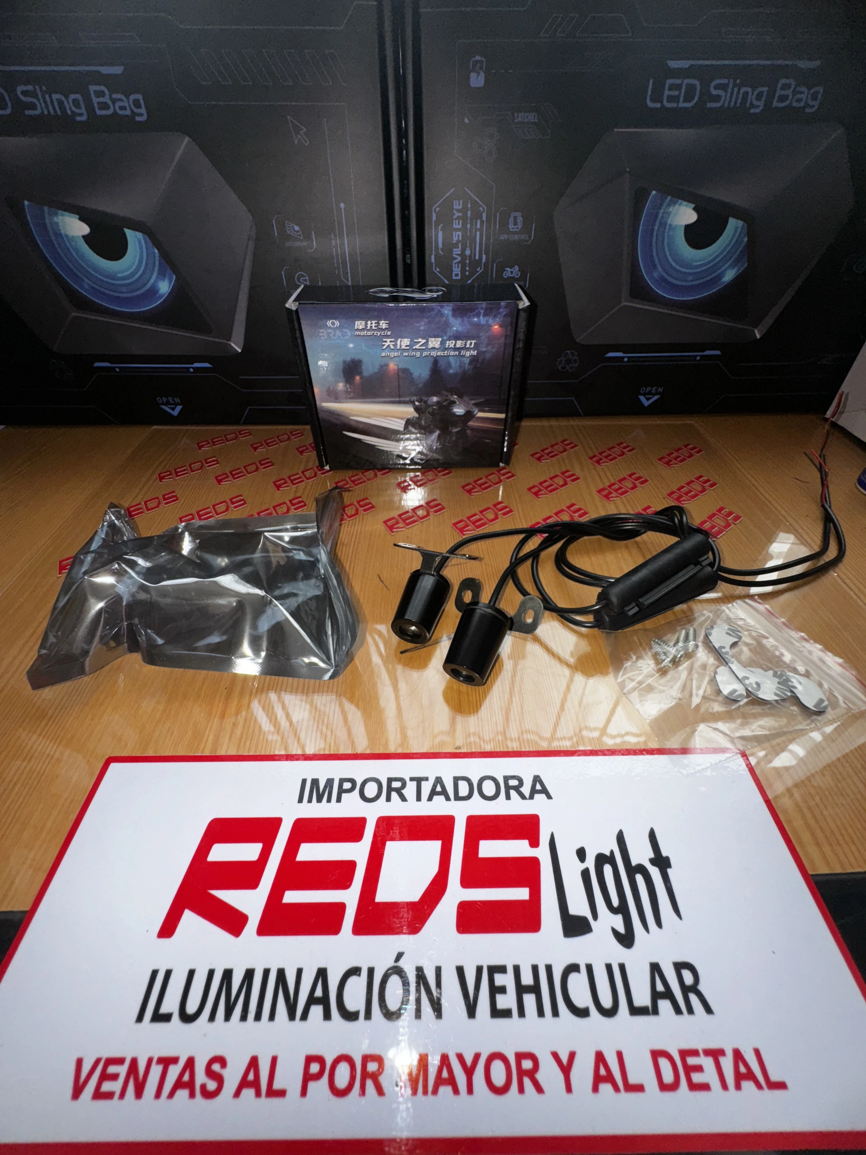 Kit de luces LED para vehículo con cables, conectores y accesorios en caja, sobre mesa con cartel de importadora.