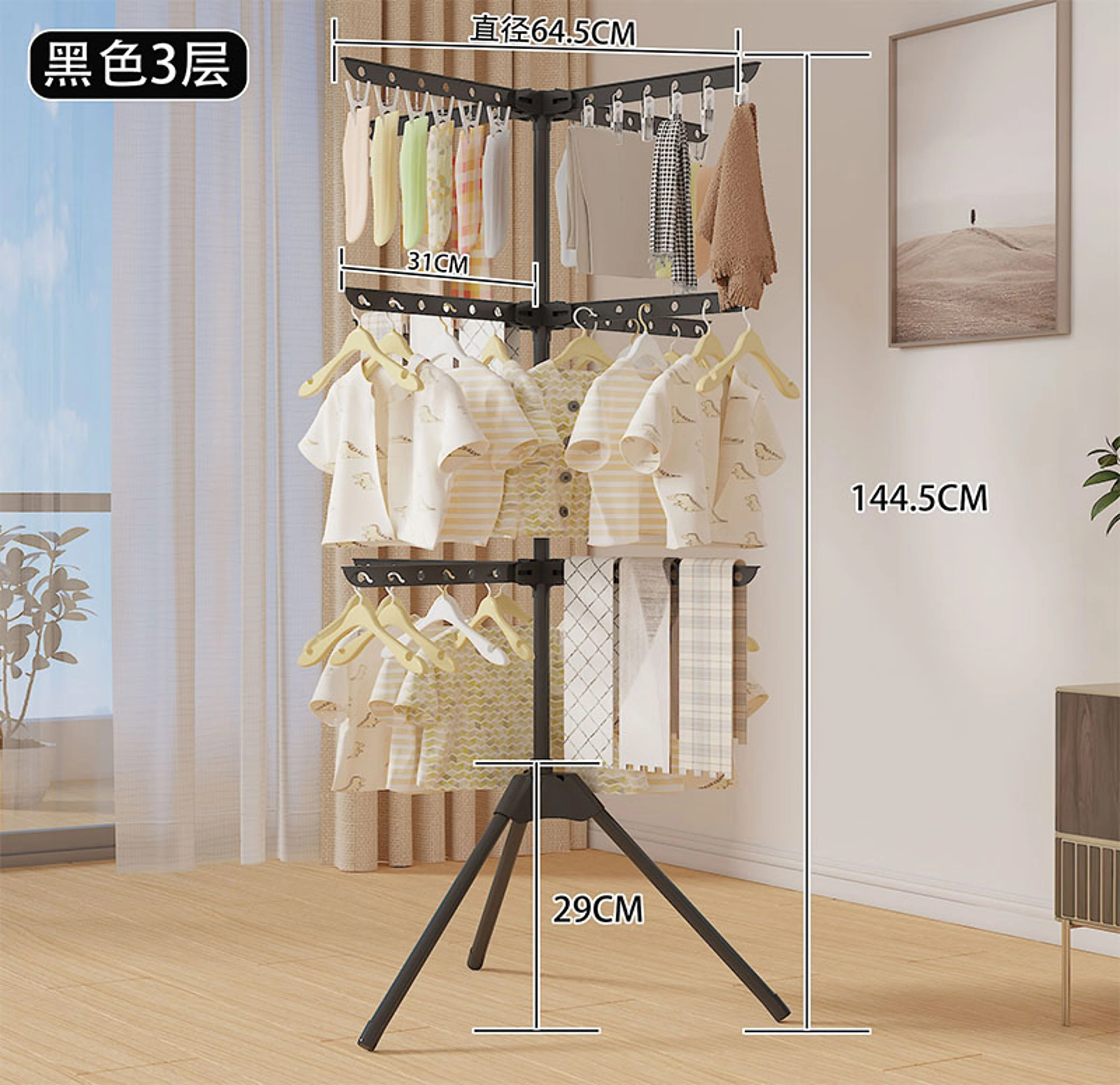 Tendedero giratorio triple de 3 niveles en color negro, con medidas de 64,5 cm de diámetro, 144,5 cm de altura y 29 cm de base. Muestra ropa infantil colgada en cada nivel, ubicado en un ambiente interior con luz natural.