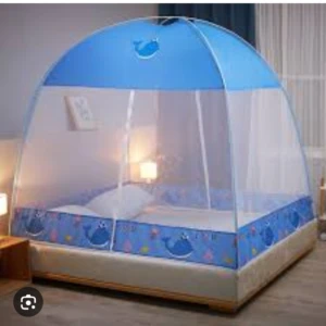 Toldillo tipo casa con malla azul y estampado de ballenas, instalado sobre cama con colchón blanco y almohada.