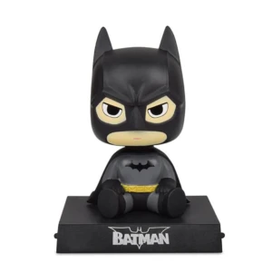 Figura de Batman sentado con cabeza movible, sobre base negra con logo, diseñada como soporte para móvil y decoración de tablero.