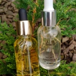 Dos frascos de sérum con gotero, uno dorado y otro transparente, sobre ramas verdes. Etiquetas visibles: "Día" y "Noche".