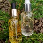 Dos frascos de vidrio con gotero: uno con sérum amarillo etiquetado como Día, otro transparente con sérum claro etiquetado como Noche, ambos sobre follaje verde.