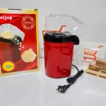 Crispetera eléctrica roja con tapa transparente, cable negro y caja de cartón al lado.