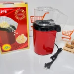 Crispetera mini eléctrica roja con tapa transparente, cable negro y caja de cartón al lado.