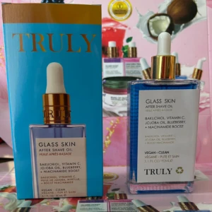 Set de dos botellas de aceite corporal Glass Skin de Truly, con dropper blanco y etiqueta azul claro; incluye caja y botella transparente con líquido azul.