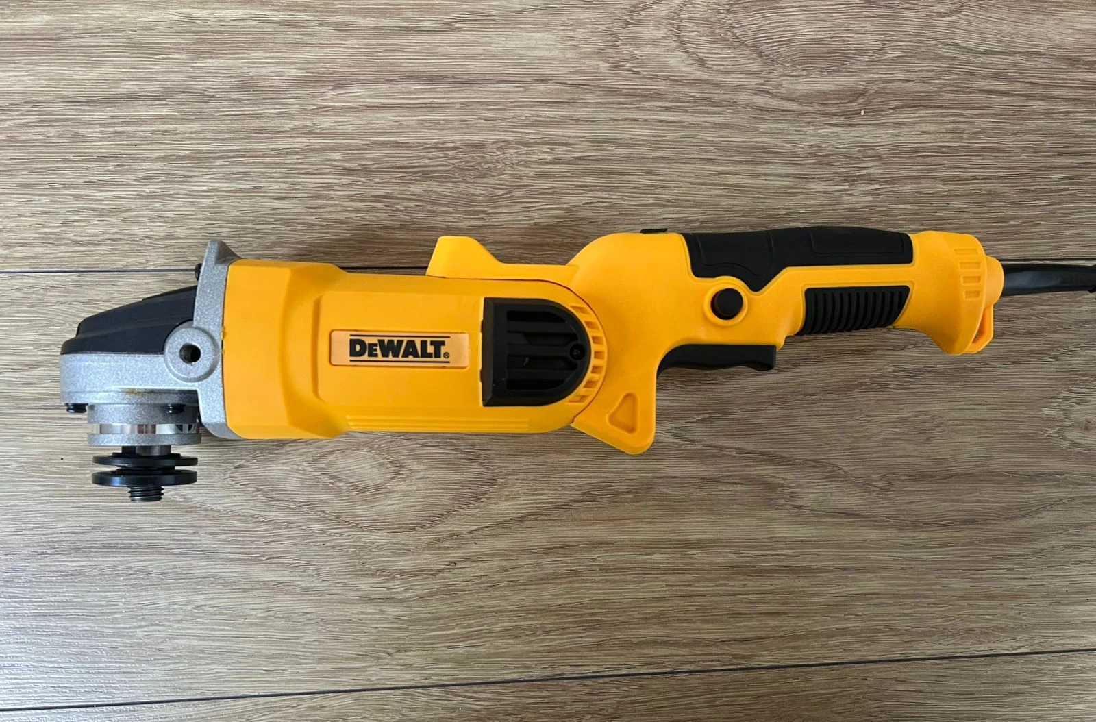 Pulidora angular Dewalt amarilla con mango negro, vista lateral sobre superficie de madera.