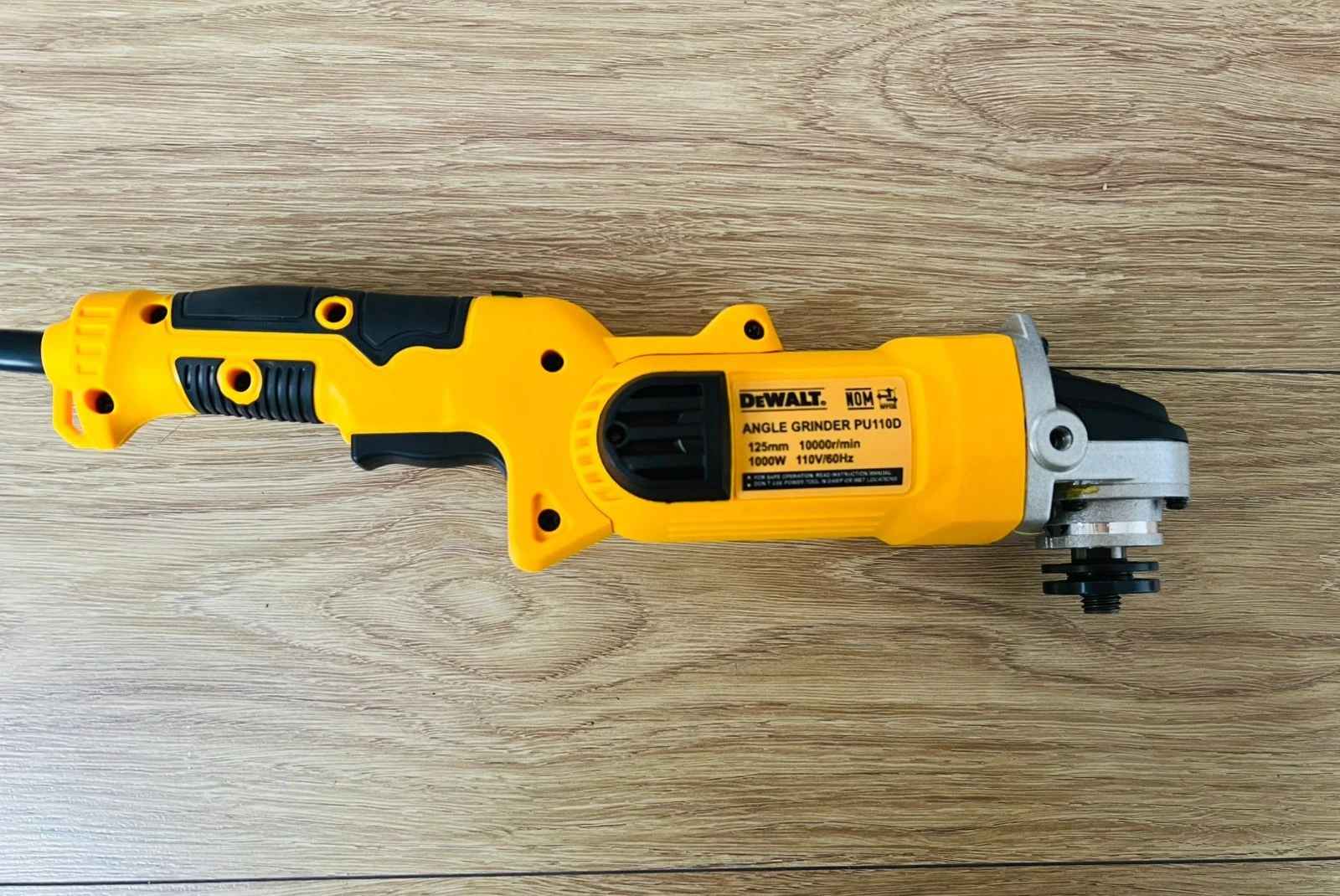 Pulidora angular Dewalt modelo PWT100, color amarillo y negro, sobre superficie de madera clara.