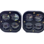 Dos faros cuadrados de color negro con cuatro lentes redondas, uno a la izquierda y otro a la derecha, sobre fondo blanco.