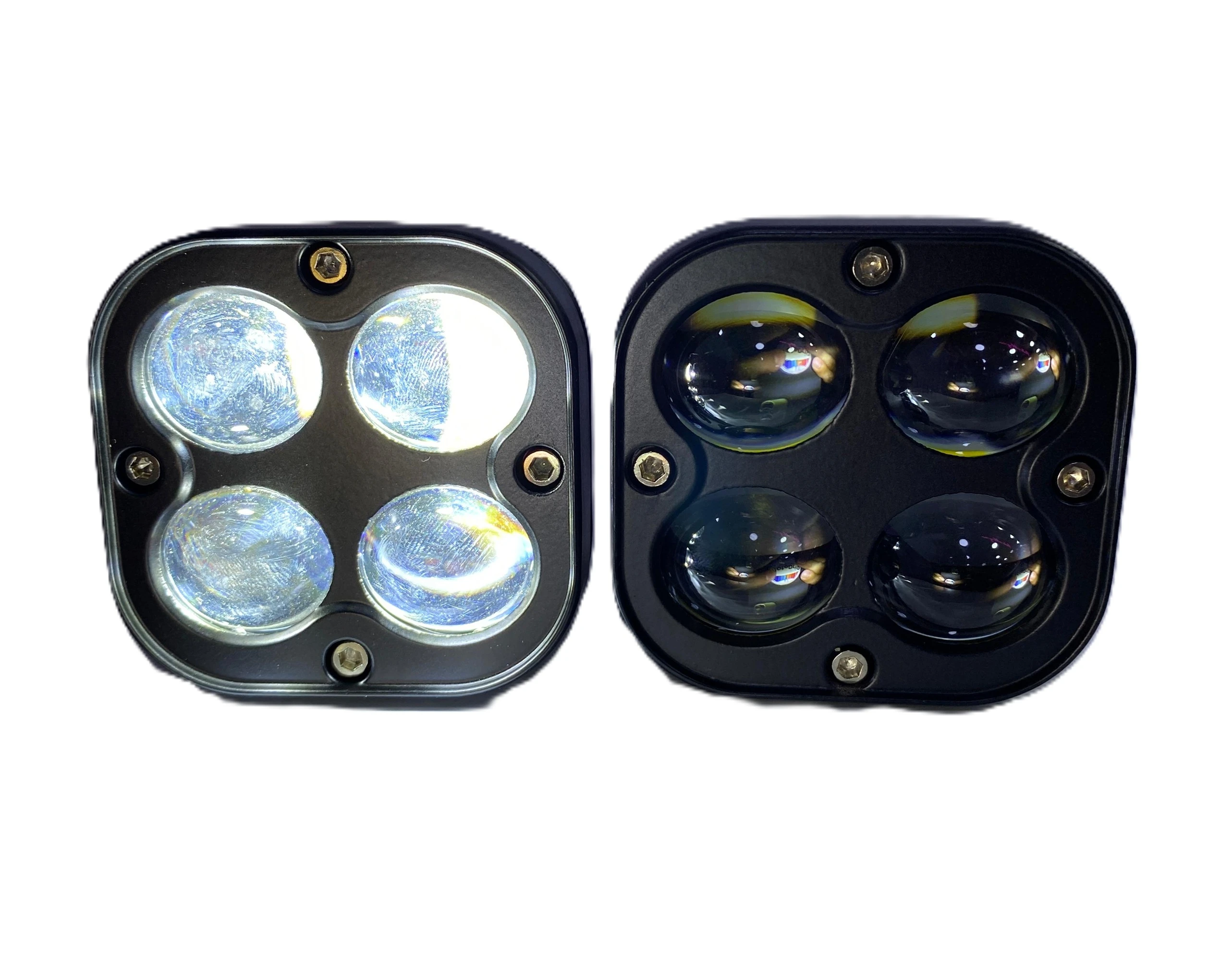 Dos faros cuadrados de exploración con cuatro lentes, uno encendido en blanco y otro apagado en amarillo, montados sobre carcasa negra.