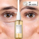 Aceite limpiador facial con Centella Asiática de Madagascar, en presentación de 200 ml. Botella transparente con líquido dorado y etiqueta blanca. Fondo con primer plano de ojos y piel, mostrando efecto calmante y limpieza sin resecar.
