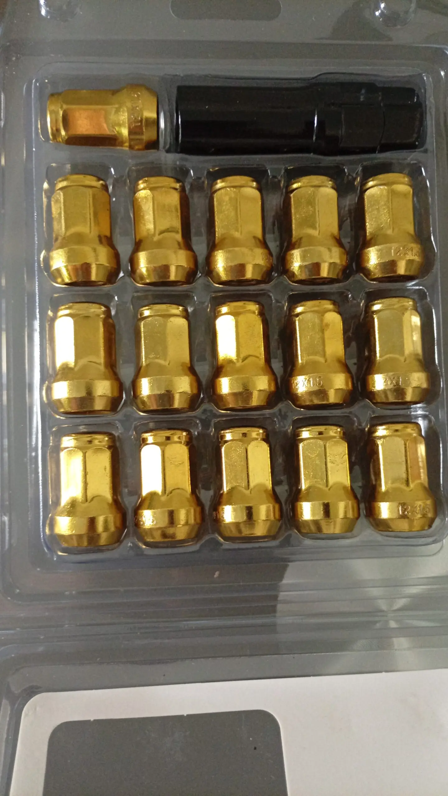 Pack de pernos de lujo dorados para ruedas, con centro negro, organizados en blister transparente.
