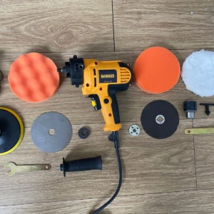 Polichadora Dewalt amarilla con accesorios incluidos: discos de corte, pulidores naranjas y blancos, cepillo, llaves y mango extra, dispuestos sobre superficie de madera.