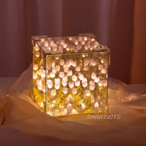 Lámpara cúbica de tulipanes con luz LED cálida, efecto espejo infinito, sobre tela suave en tono rosado.