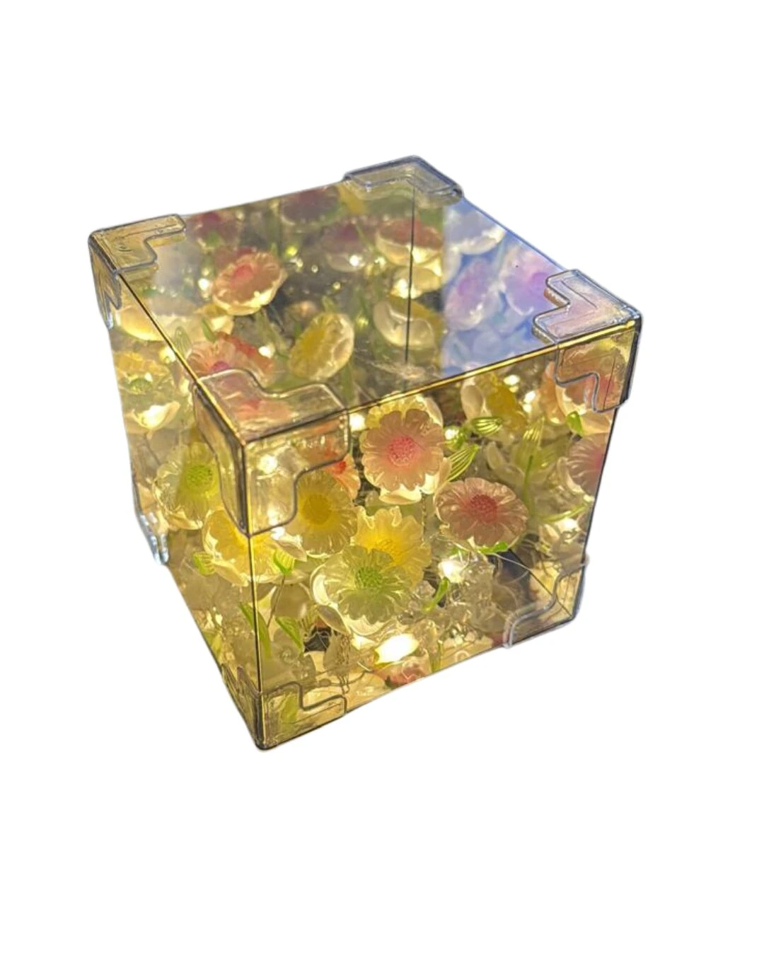 Cubo transparente con girasoles y luces LED cálidas, efecto espejo en las caras, ideal para ambientación decorativa.