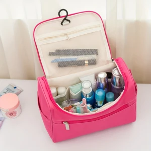 Bolsa de aseo rosa con gancho colgante, abierta y mostrando cosméticos organizados en compartimentos internos.