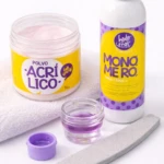 Kit de uñas en acrílico con polvo rosa y monómero en botella blanca con tapa morada, junto a esmerilador, tapa y recipiente pequeño con líquido púrpura.
