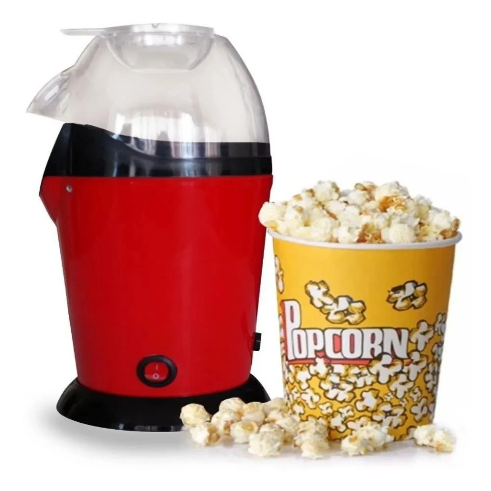 Crispetera de aire compacta roja con tapa transparente, junto a palomitas en taza amarilla y algunas sueltas sobre superficie blanca.