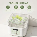 Dispositivo de limpieza portátil para biberones en blanco con detalles en verde claro, mostrando cepillos de silicona y accesorios dentro de su estuche transparente. Panel frontal con pantalla digital y controles táctiles.