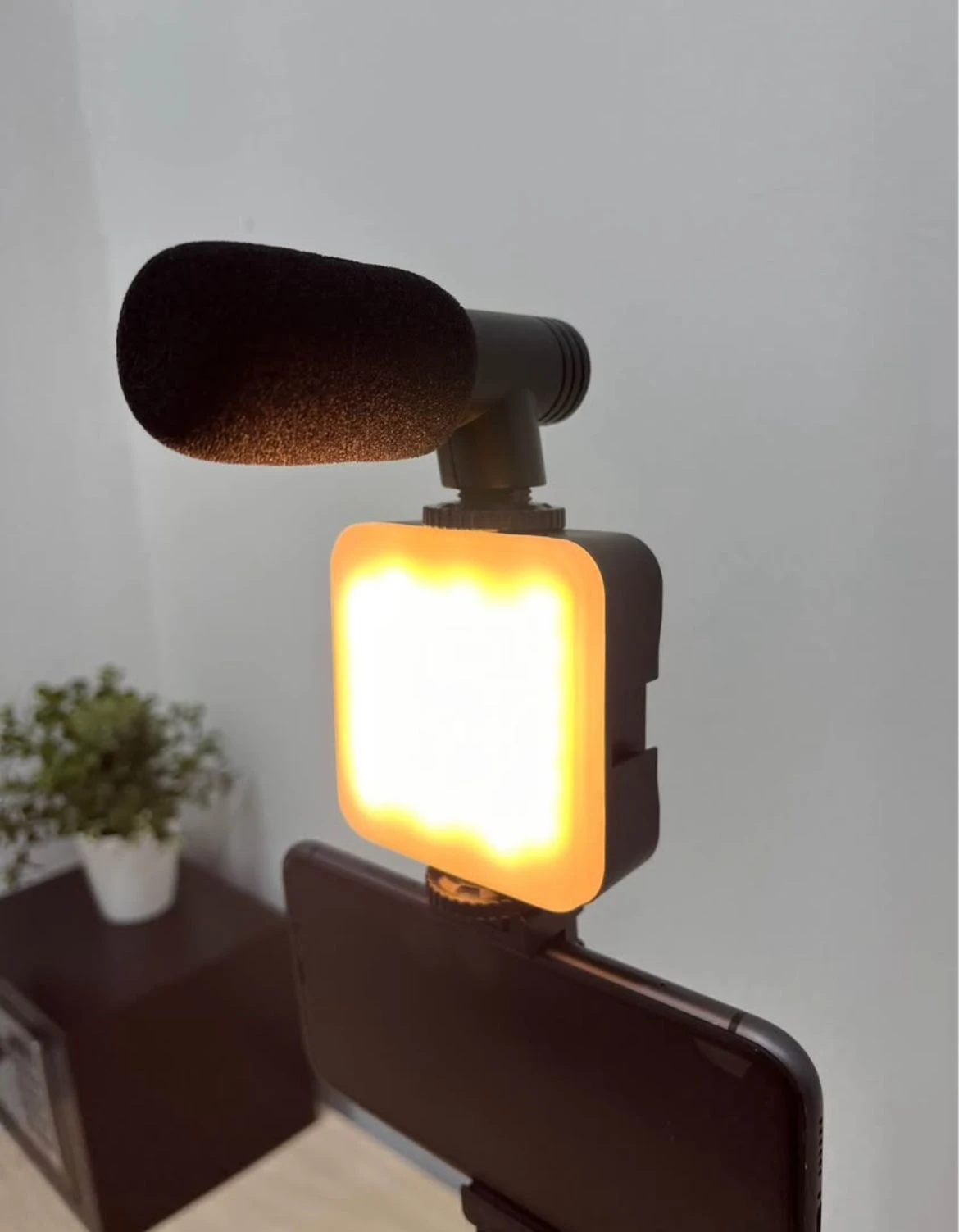 Kit de video con luz LED RGB encendida y micrófono de solapa montado sobre smartphone, ideal para grabaciones profesionales.