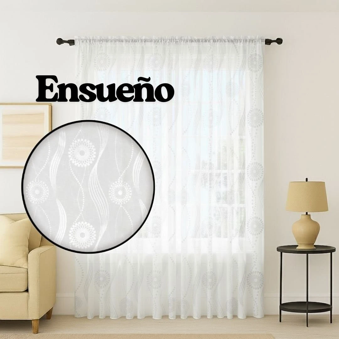 Cortina de velo muselina blanca con estampado floral sutil, colgada en ventana con varilla oscura, en sala con sillón y lámpara lateral.