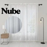 Cortina de velo muselina blanca, modelo Nube, con textura visible en primer plano. Incluye varilla de montaje y se muestra colgada en sala con lámpara y mueble lateral.