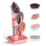 Cepillo de limpieza rosa con jabón integrado y cabezas intercambiables para ollas y platos, mostrando accesorios desmontados.