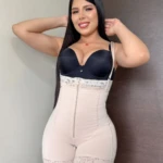 Faja modeladora cremallera frontal en color nude con top negro, vista frontal de modelo sonriendo con brazos levantados.