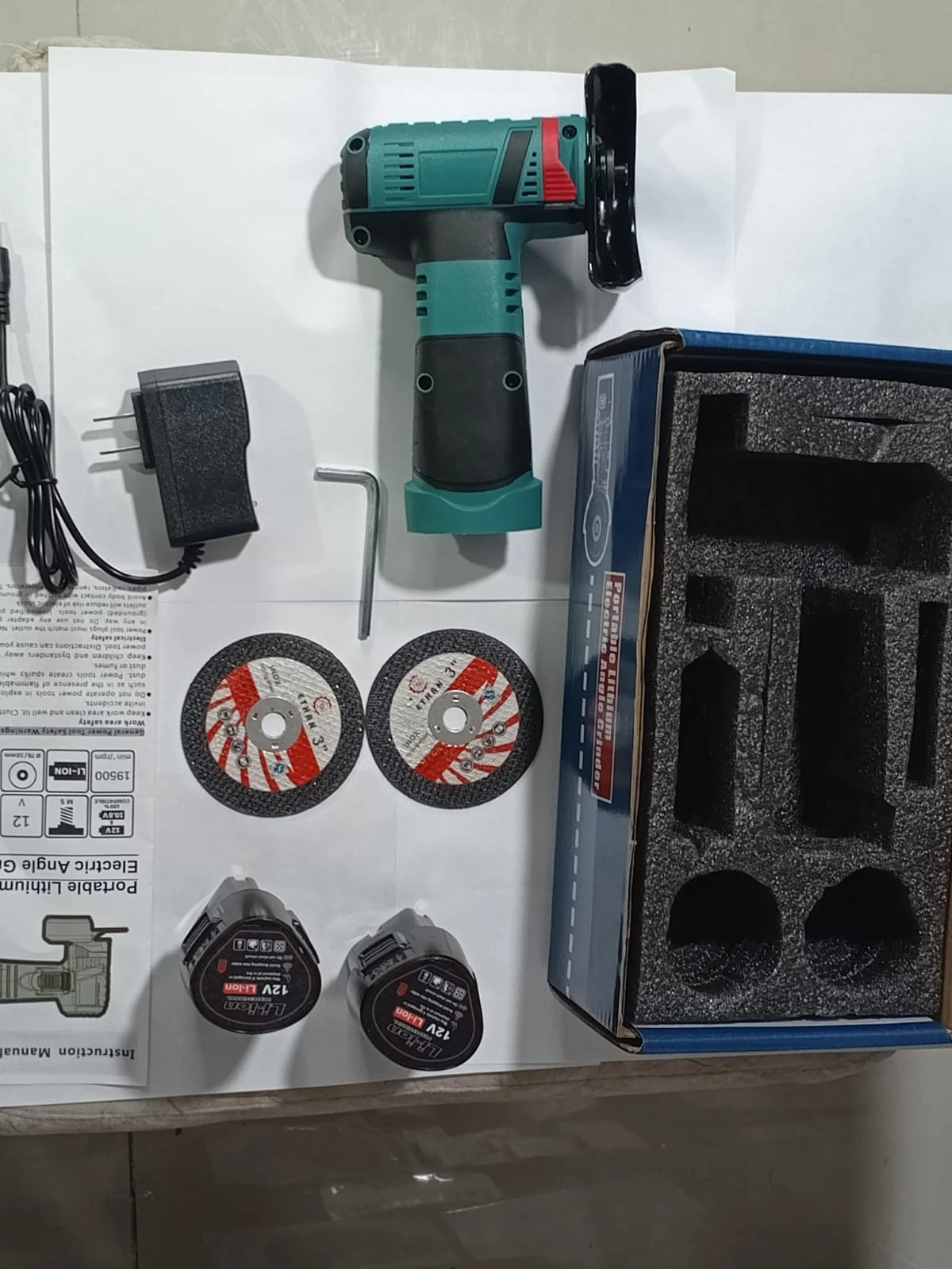 Mini pulidora inalámbrica de 12V en color verde y negro, con accesorios incluidos: dos discos de corte, cargador, llave Allen y caja de transporte con espuma protectora.