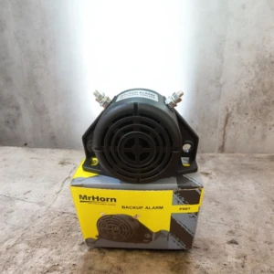 Pito de reversa automático MrHorn modelo F007, color negro, sobre su caja amarilla con detalles grises, montado en base metálica con tornillos visibles, diseñado para vehículos y maquinaria.