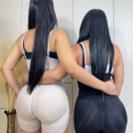 Dos mujeres con fajas Strapple de espalda, una en color crema y otra en negro, mostrando la cremallera frontal y ajuste en cintura y cadera.