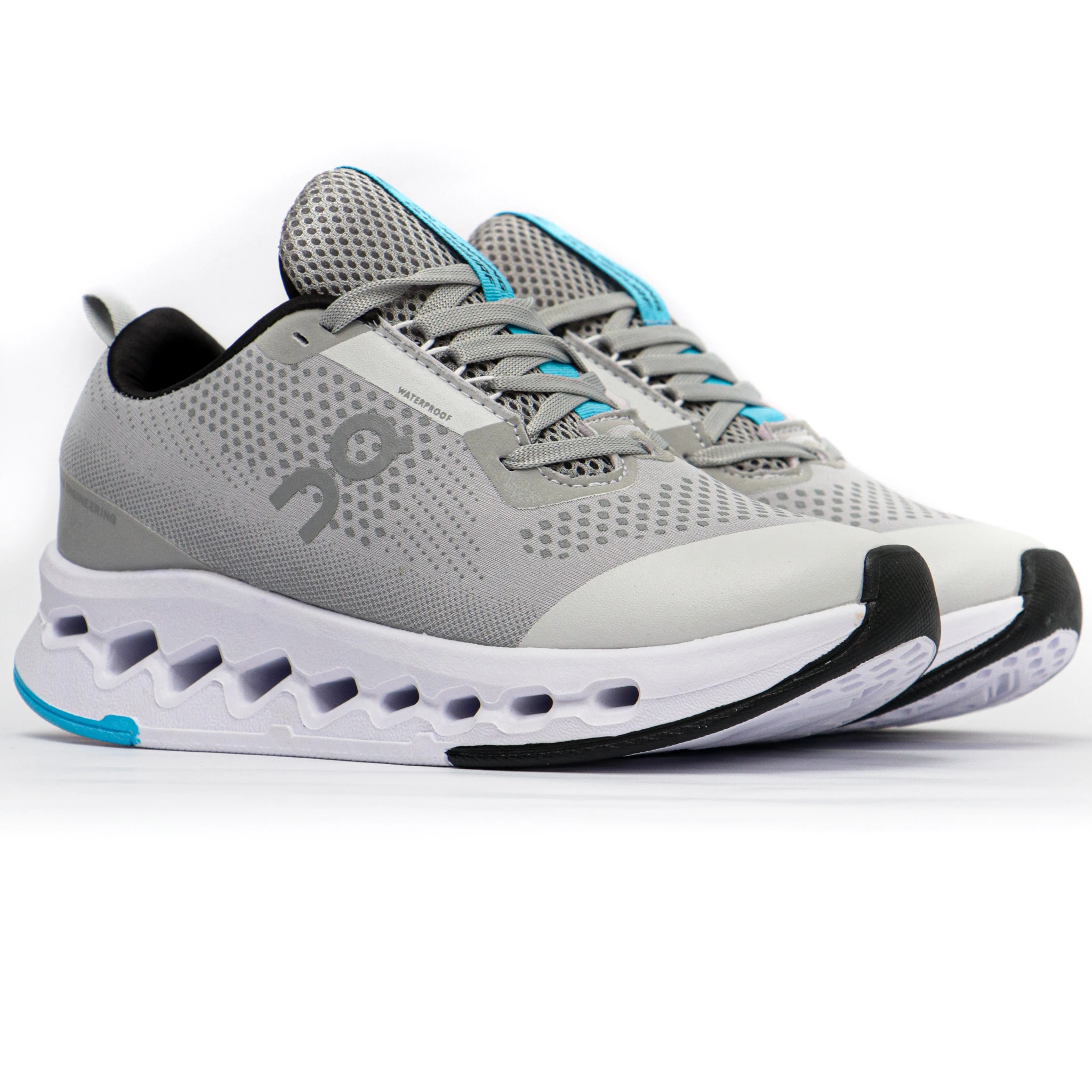 Zapatilla deportiva On6 en gris con detalles azul y negro, malla transpirable y suela segmentada para amortiguación. Vista lateral sobre fondo blanco.