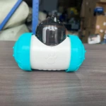 Dispensador interactivo para perros en color azul turquesa y blanco, con tapa transparente y huella de pata grabada en la parte frontal.