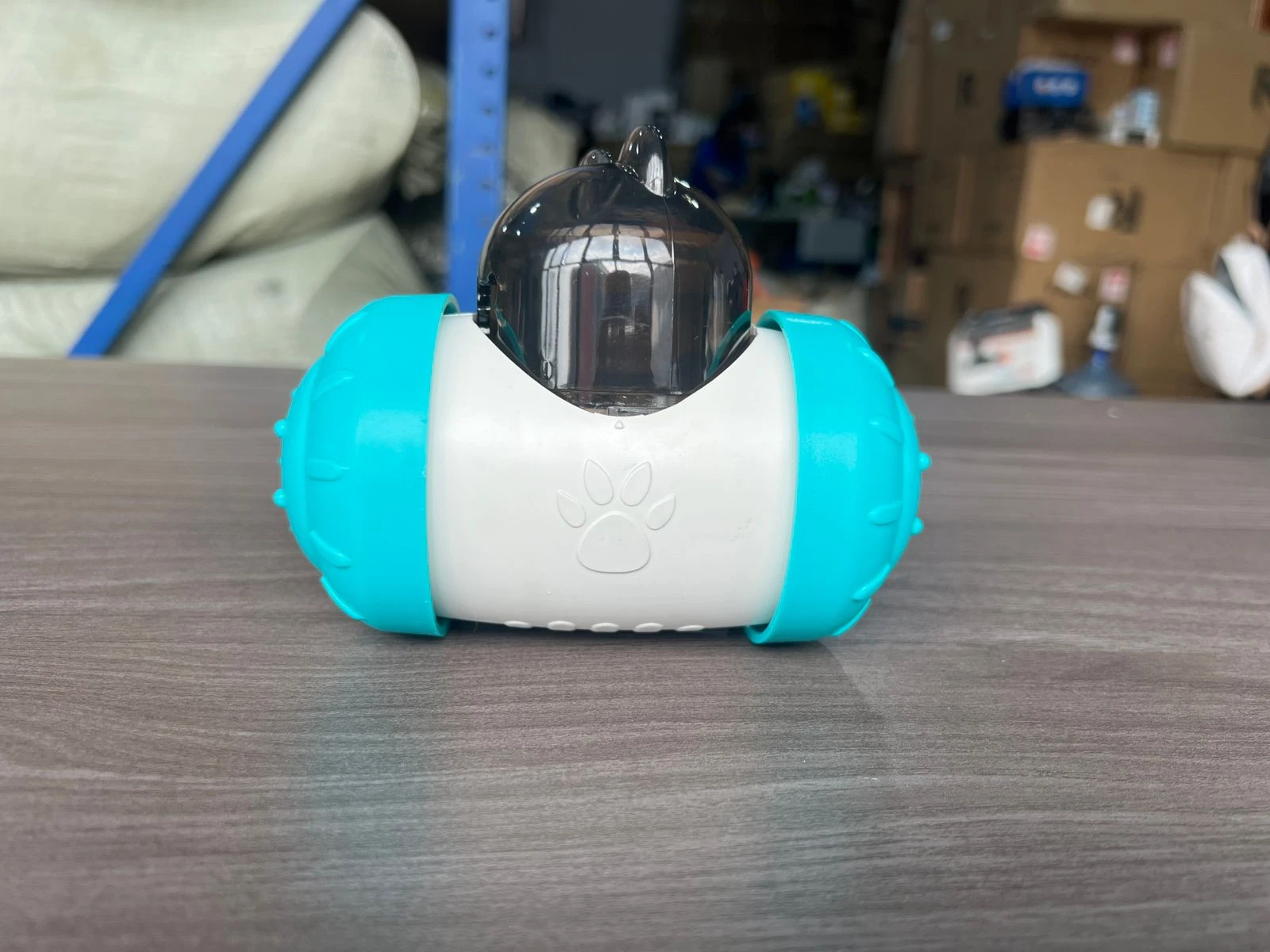 Dispensador interactivo para perros en color azul turquesa y blanco, con tapa transparente y huella de pata grabada en la parte frontal.