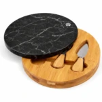 Tabla redonda de quesos con superficie de mármol negro y base de bambú, incluye dos utensilios integrados para servir.