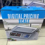 Bascula de mesa digital de 40 kg con calculadora integrada, mostrada en su caja azul y blanca con frontal del dispositivo y detalles de uso en entorno comercial.