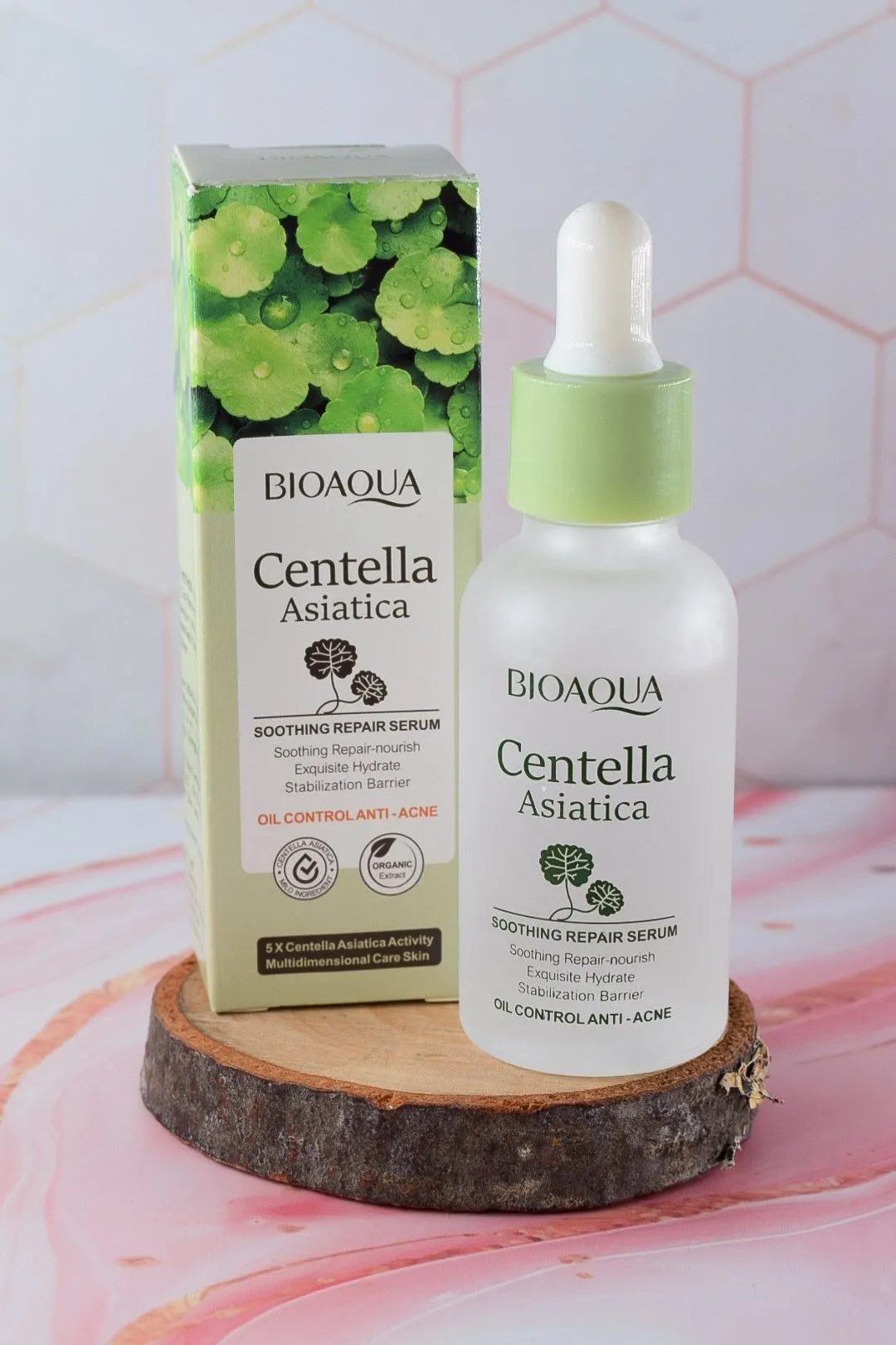 Serum regenerador Centella Asiática de Bioaqua en presentación de vidrio blanco con gotero verde, acompañado de su caja con de hojas, sobre base de madera.