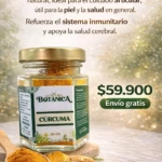 Jarrón de vidrio con tapa dorada que contiene cúrcuma en polvo, acompañado de raíz fresca y cuchara de madera, sobre superficie clara con fondo desenfocado.