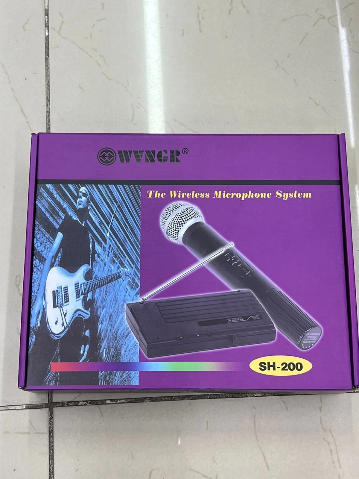 Caja morada del sistema de micrófono inalámbrico Wyngir SH-200, mostrando el micrófono con antena retráctil y la base receptora. Incluye de músico con guitarra.
