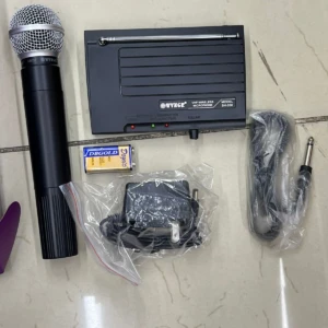 Micrófono inalámbrico VHF Wyngir SH-200 con antena retráctil, base de carga, cable de audio y batería en caja.