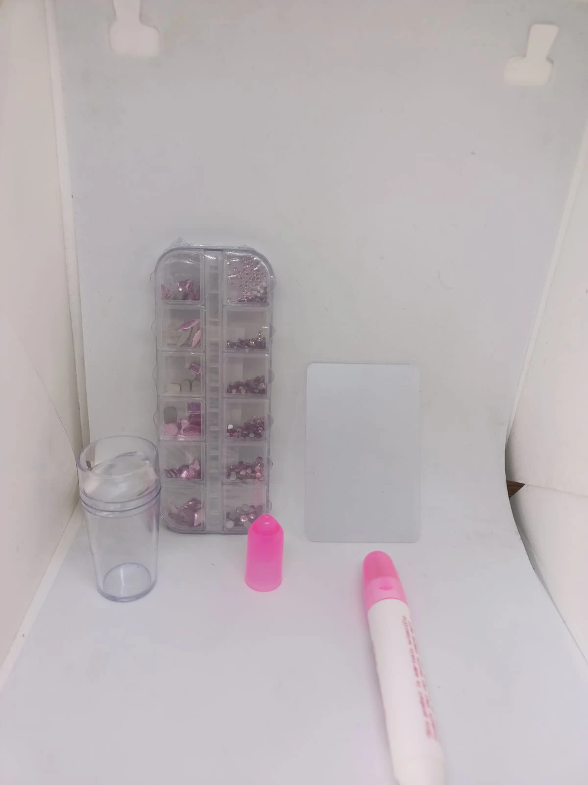 Kit de decoración para uñas con piedras y estampador. Incluye organizador transparente con accesorios, tóner rosa, base de silicona y rodillo para estampado.