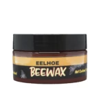 Tarro de cera de abeja natural de 100 g con tapa negra y etiqueta amarilla y negra, ideal para restaurar y proteger muebles y suelos.