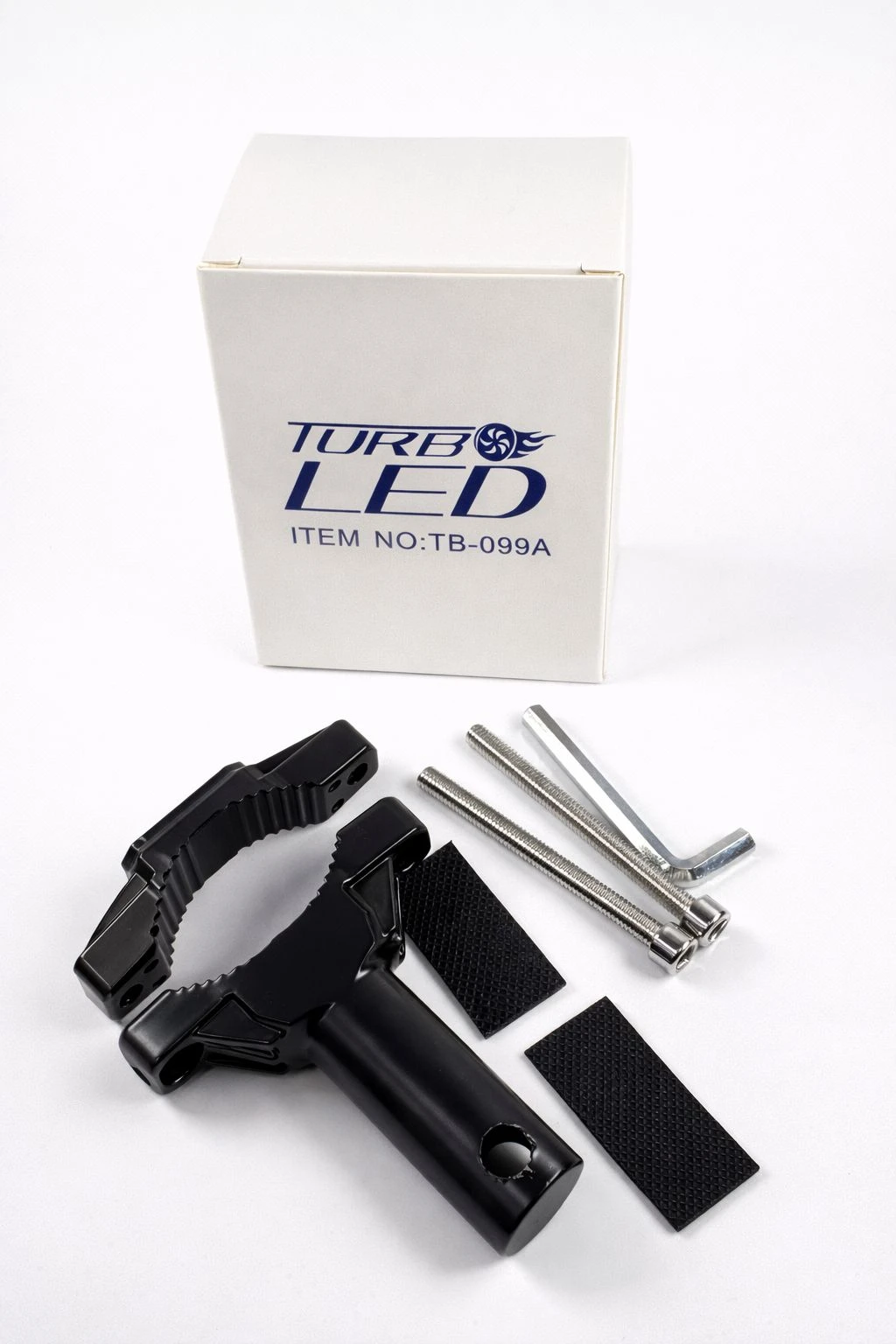 Kit de montaje para faro TK-01A: abrazadera negra con sujeción dentada, dos tiras adhesivas y tres tornillos hexagonales, junto a caja blanca con logo Turb LED.