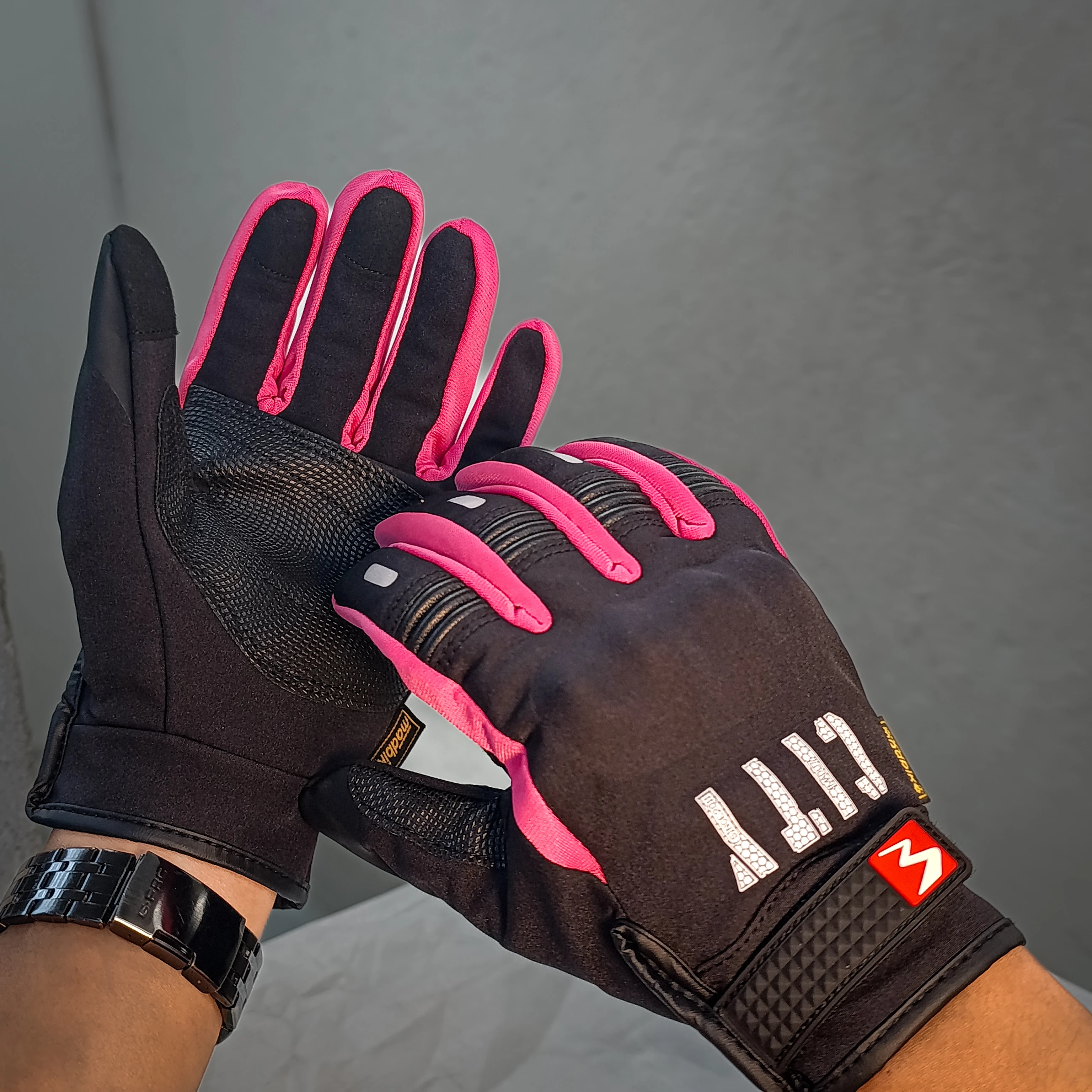 Guante City negro con detalles rosa, diseño táctil para uso en celular, muestra palma y dorso con textura antideslizante y logo visible.