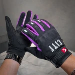 Guante City negro con detalles en morado, diseño táctil para uso en el celular mientras se conduce, con logo visible en la muñeca.