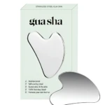 Gua sha de acero inoxidable en color plateado, con forma ergonómica y acabado pulido, acompañado de su caja de presentación en tono verde claro.
