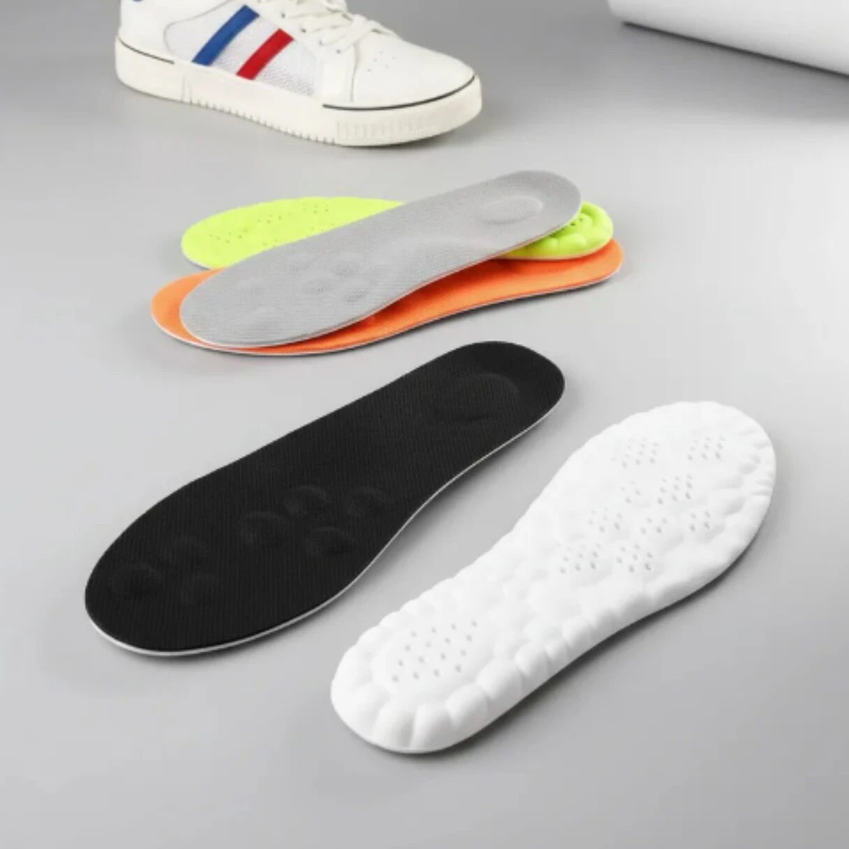 Plantillas deportivas acolchadas en colores blanco, negro, naranja y verde lima, con base antideslizante y diseño ergonómico para caminar.