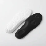 Plantillas deportivas acolchadas en blanco y negro, con base antideslizante y diseño ergonómico para mejorar estabilidad y reducir fatiga al caminar.