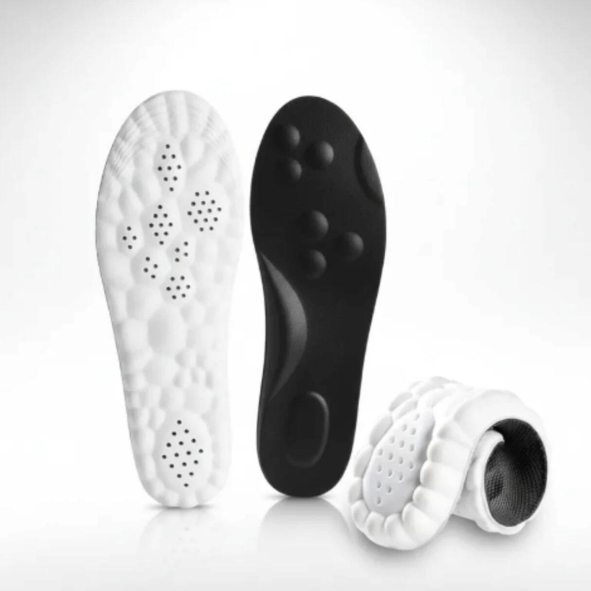 Plantillas deportivas acolchadas en blanco y negro, con base antideslizante y perforaciones para ventilación. Presentación de dos unidades, una enrollada, mostrando textura y diseño ergonómico.